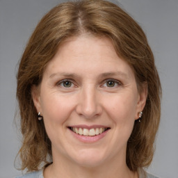 Joyful white adult female with medium  brown hair and grey eyes