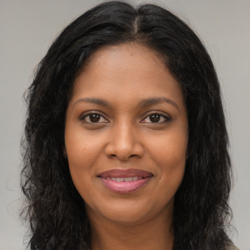 Joyful black young-adult female with long  brown hair and brown eyes