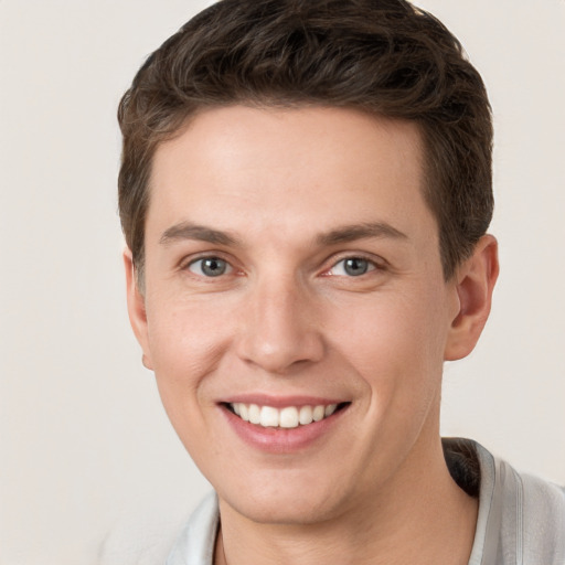 Joyful white young-adult male with short  brown hair and grey eyes