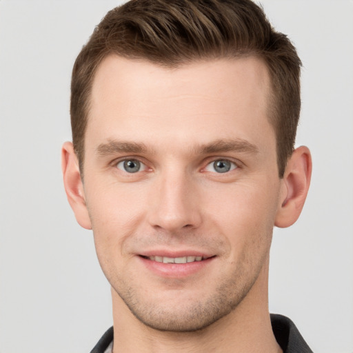 Joyful white young-adult male with short  brown hair and grey eyes