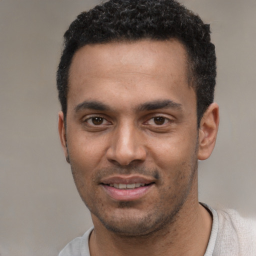 Joyful black young-adult male with short  black hair and brown eyes