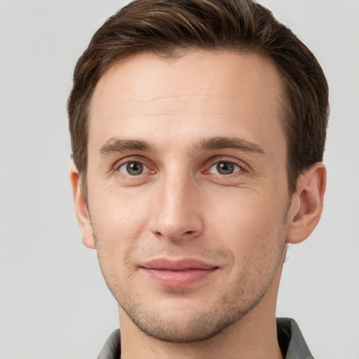 Joyful white young-adult male with short  brown hair and grey eyes