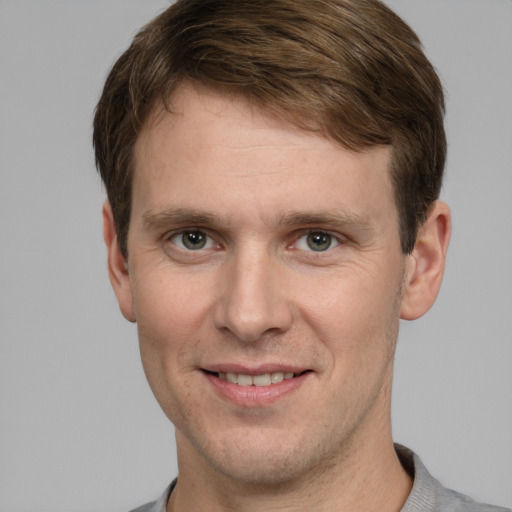 Joyful white young-adult male with short  brown hair and grey eyes