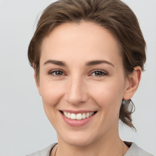 Joyful white young-adult female with short  brown hair and grey eyes