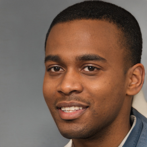 Joyful black young-adult male with short  brown hair and brown eyes