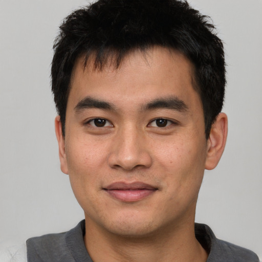 Joyful asian young-adult male with short  black hair and brown eyes