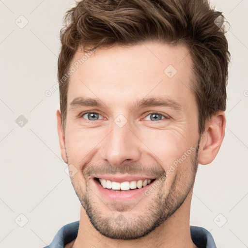 Joyful white young-adult male with short  brown hair and grey eyes