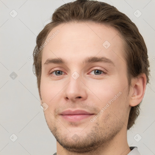 Joyful white young-adult male with short  brown hair and grey eyes