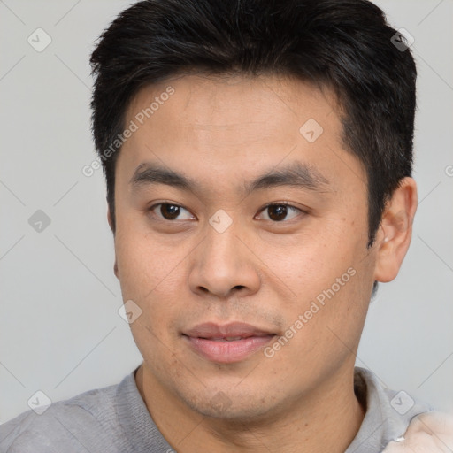 Joyful asian young-adult male with short  brown hair and brown eyes