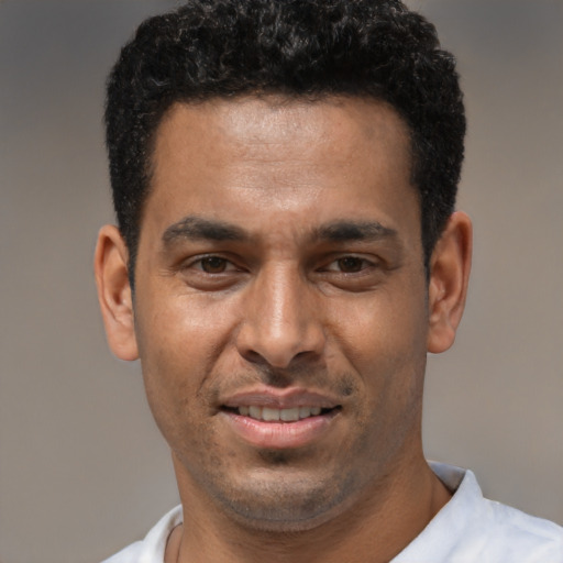 Joyful latino young-adult male with short  black hair and brown eyes
