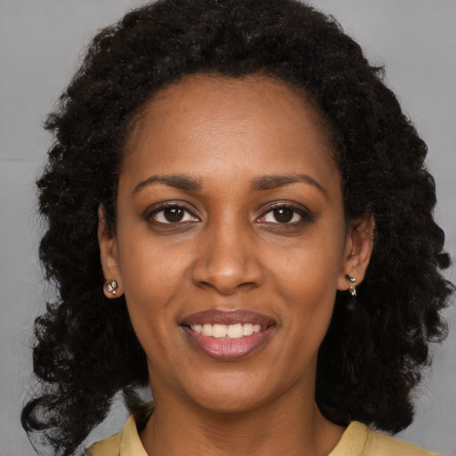 Joyful black young-adult female with long  black hair and brown eyes