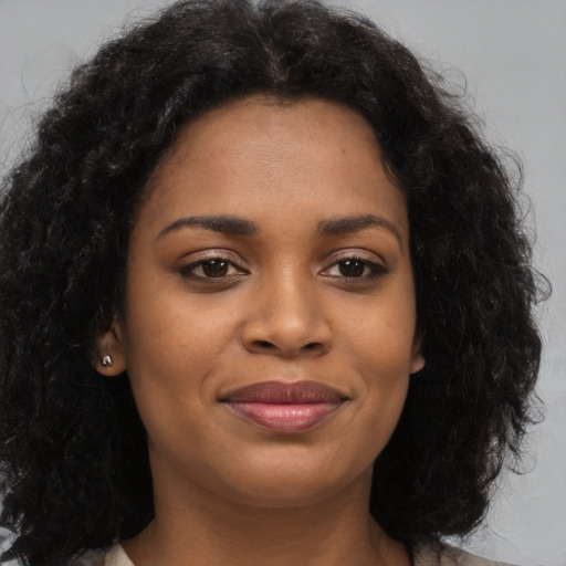 Joyful black young-adult female with long  brown hair and brown eyes