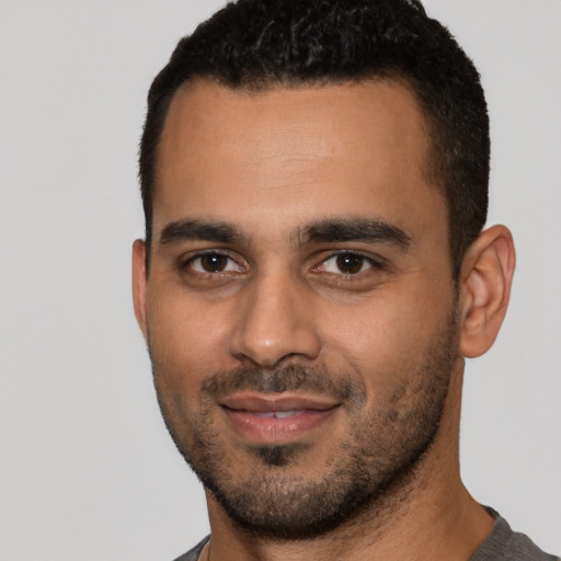 Joyful latino young-adult male with short  black hair and brown eyes