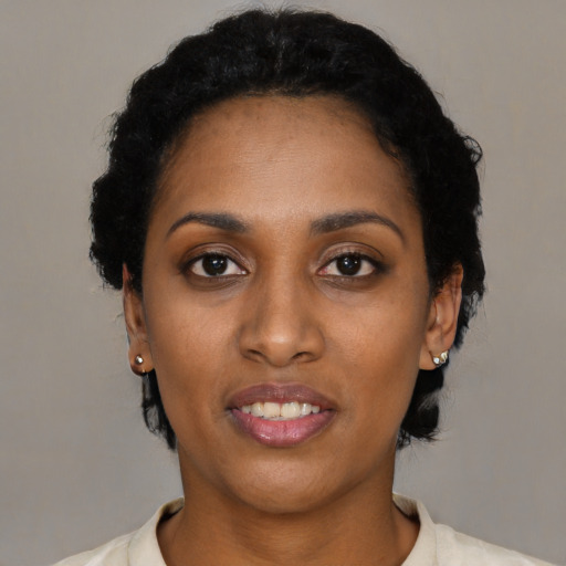 Joyful black young-adult female with short  black hair and brown eyes