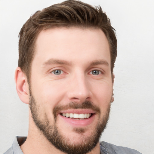 Joyful white young-adult male with short  brown hair and grey eyes