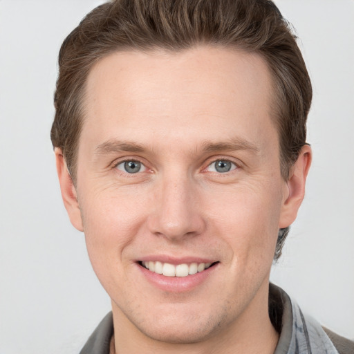 Joyful white young-adult male with short  brown hair and grey eyes