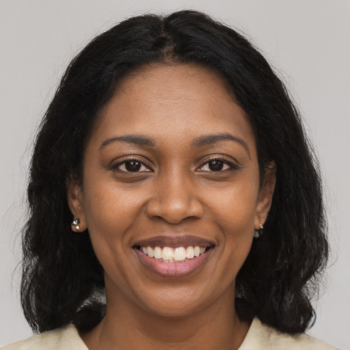 Joyful black young-adult female with long  black hair and brown eyes