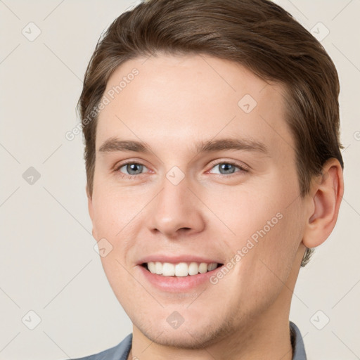 Joyful white young-adult male with short  brown hair and grey eyes