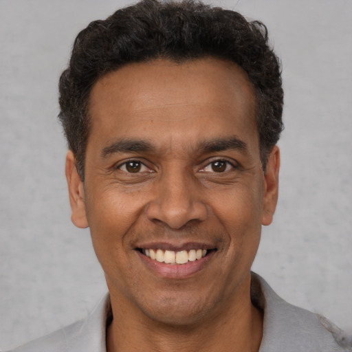 Joyful latino young-adult male with short  brown hair and brown eyes