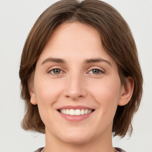 Joyful white young-adult female with medium  brown hair and green eyes