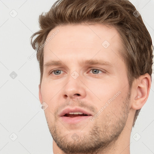 Joyful white young-adult male with short  brown hair and grey eyes