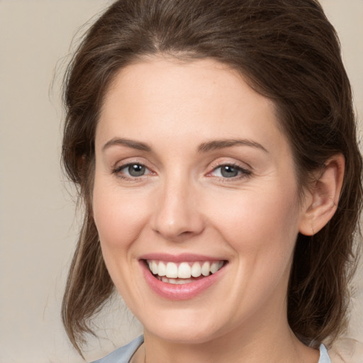 Joyful white young-adult female with medium  brown hair and grey eyes