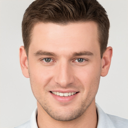 Joyful white young-adult male with short  brown hair and grey eyes