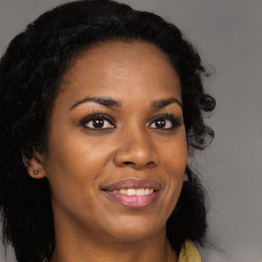 Joyful black young-adult female with long  brown hair and brown eyes