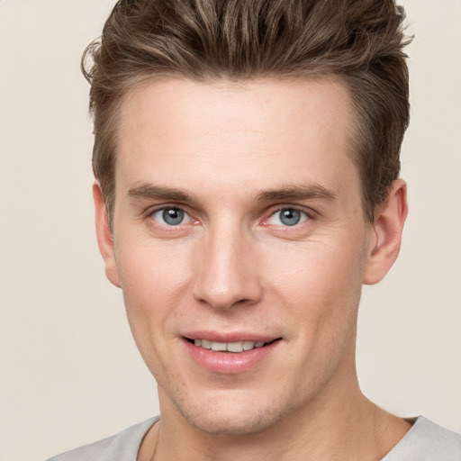 Joyful white young-adult male with short  brown hair and grey eyes