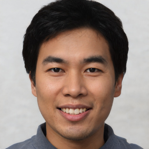 Joyful asian young-adult male with short  black hair and brown eyes
