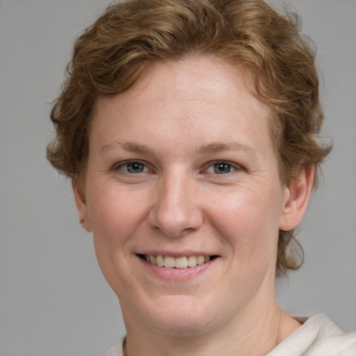 Joyful white young-adult female with short  brown hair and blue eyes