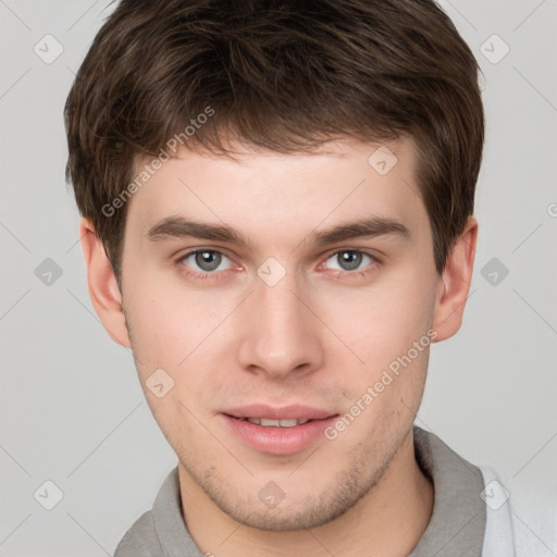 Joyful white young-adult male with short  brown hair and grey eyes