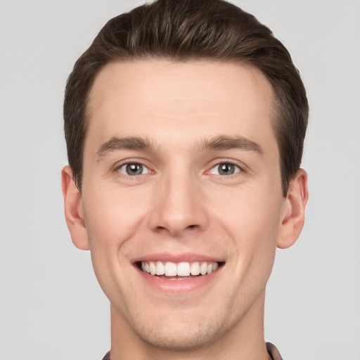 Joyful white young-adult male with short  brown hair and grey eyes