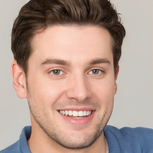 Joyful white young-adult male with short  brown hair and grey eyes