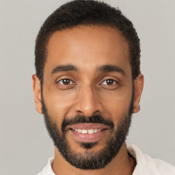 Joyful black young-adult male with short  black hair and brown eyes
