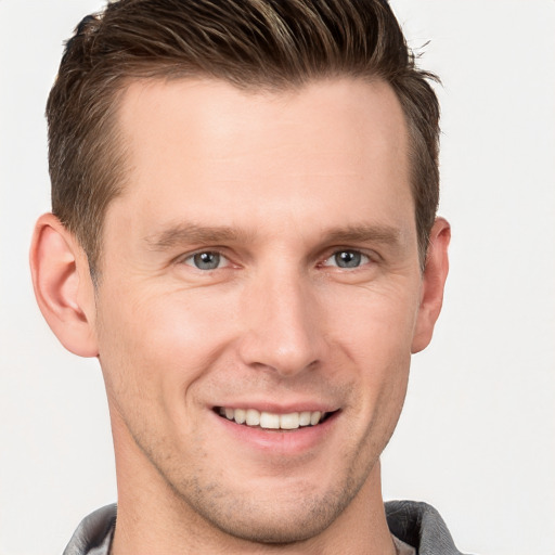 Joyful white young-adult male with short  brown hair and grey eyes