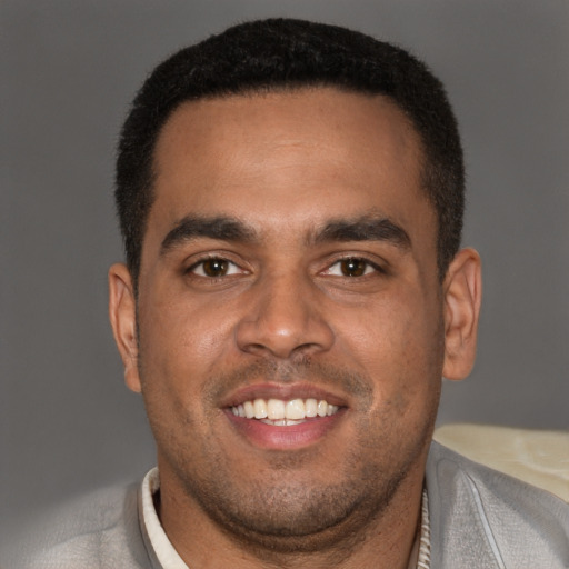 Joyful black young-adult male with short  brown hair and brown eyes