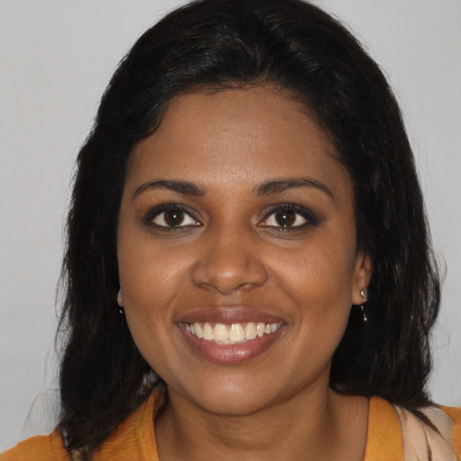 Joyful black young-adult female with long  brown hair and brown eyes
