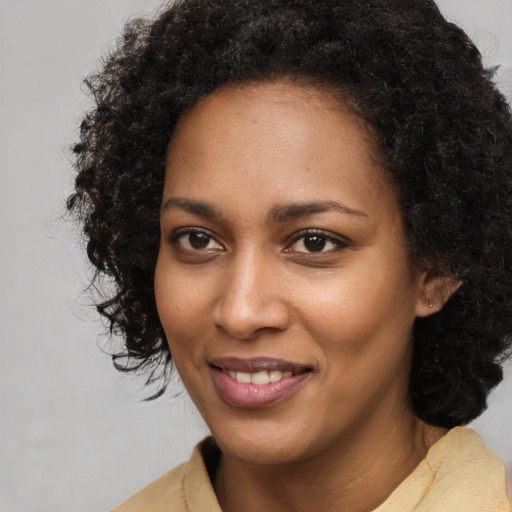 Joyful black young-adult female with long  black hair and brown eyes
