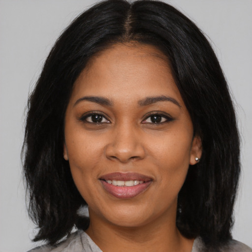 Joyful black young-adult female with long  black hair and brown eyes