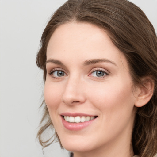 Joyful white young-adult female with long  brown hair and blue eyes