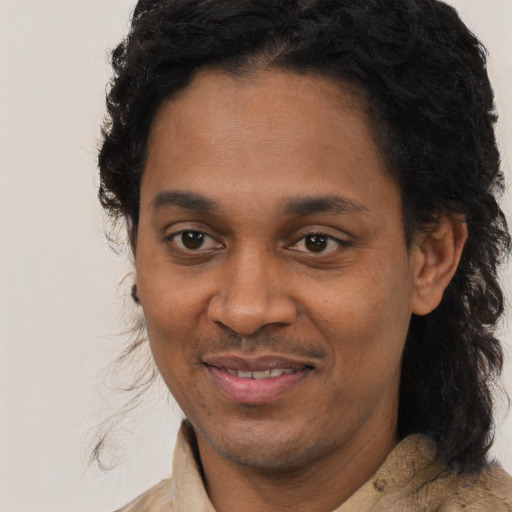 Joyful black young-adult male with long  black hair and brown eyes