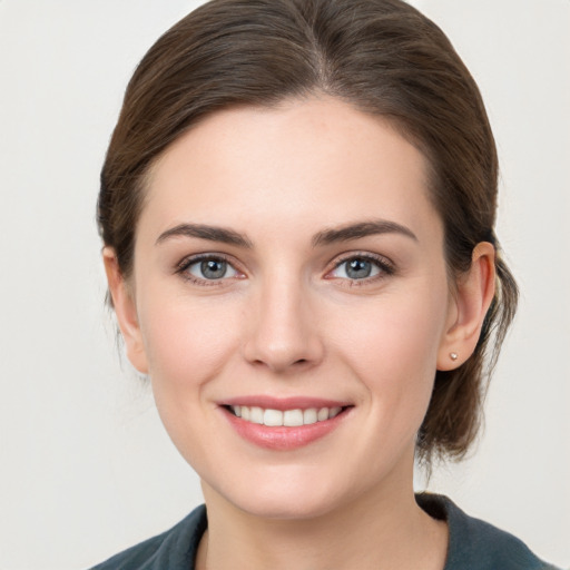 Joyful white young-adult female with medium  brown hair and grey eyes