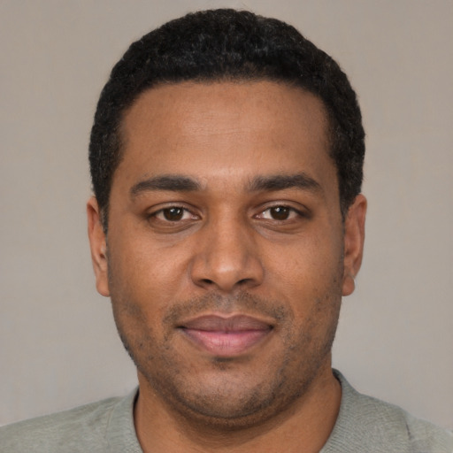 Joyful black young-adult male with short  black hair and brown eyes