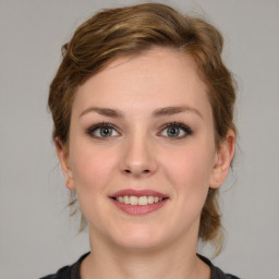 Joyful white young-adult female with medium  brown hair and grey eyes