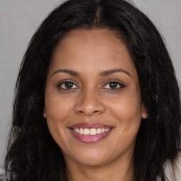 Joyful black young-adult female with long  brown hair and brown eyes