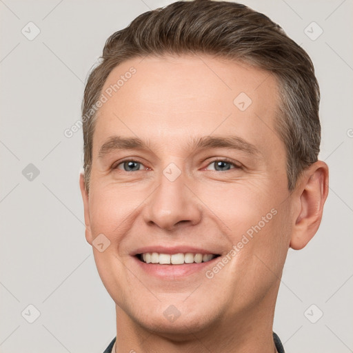 Joyful white young-adult male with short  brown hair and grey eyes