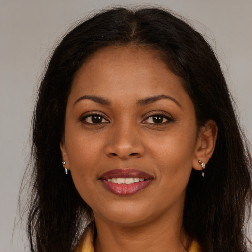 Joyful black young-adult female with long  brown hair and brown eyes