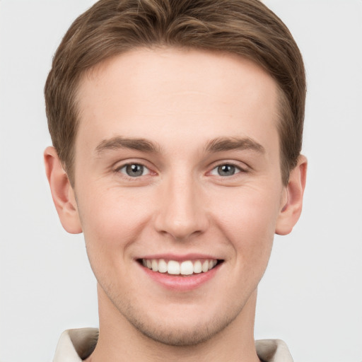 Joyful white young-adult male with short  brown hair and grey eyes