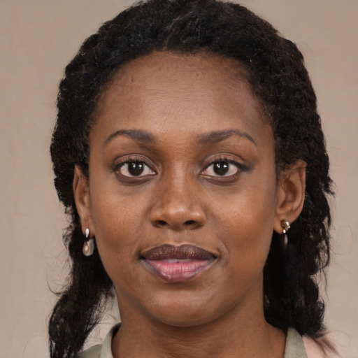 Joyful black young-adult female with long  brown hair and brown eyes